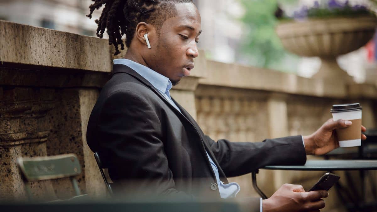 A person messaging on a smartphone in a cafe, weighing a website versus a domain and WhatsApp