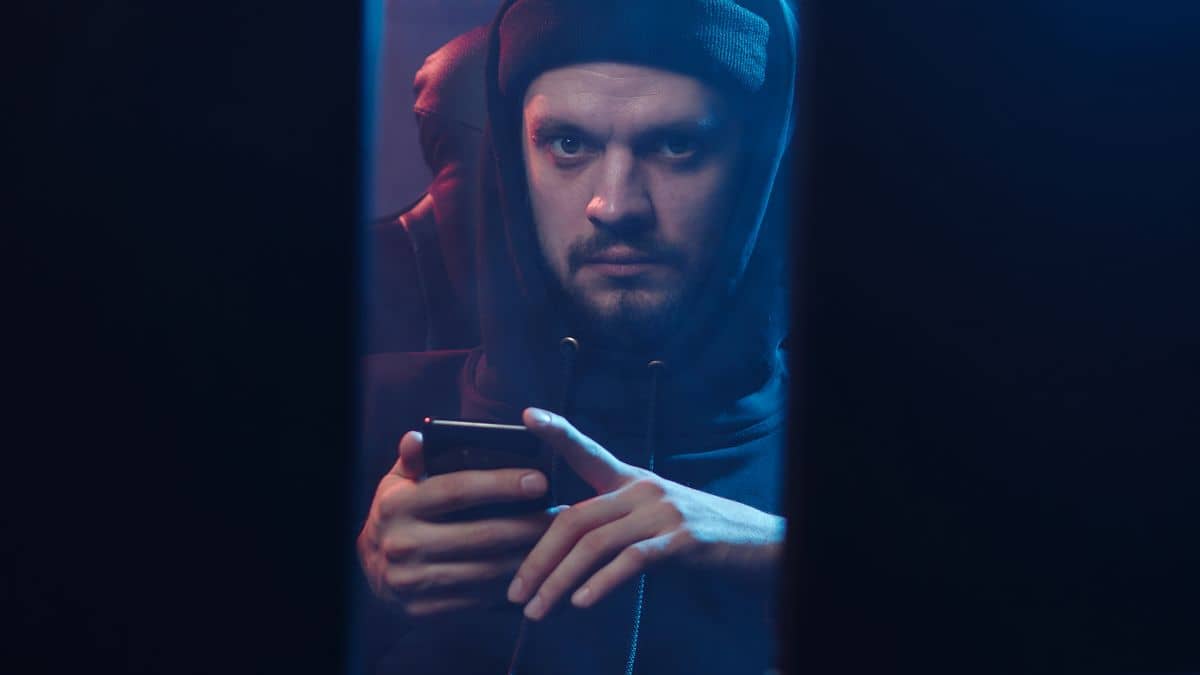 A person on a smartphone in low light, representing WHOIS data and domain privacy